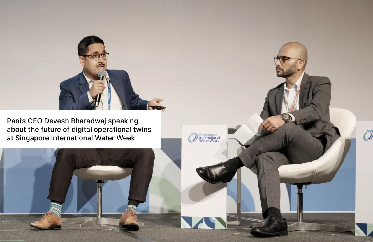 Two men sit in chairs on stage at Singapore International Water Week, with the man on the left holding a microphone