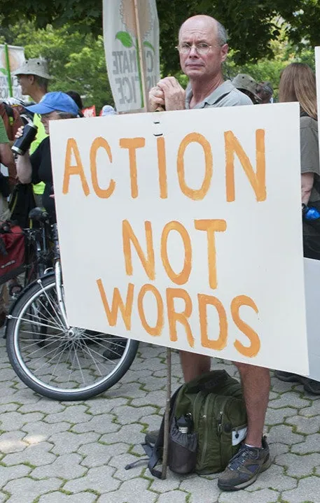 Man holds sign saying "Action not words" at a climate action protest